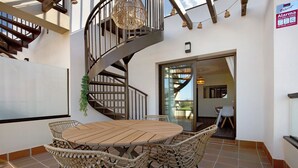 Eine Wendeltreppe, ein runder Holztisch mit Stühlen und eine Glastür, die zu einem Außenbereich führt.