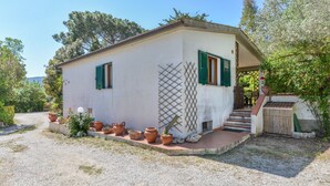 Un petit bâtiment d’un seul étage, avec une allée en gravier et des plantes en pot.