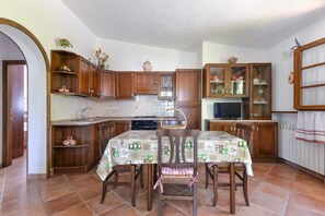 Une cuisine avec des meubles de rangement en bois, une table à manger avec des chaises, un four à micro-ondes et une cuisinière.