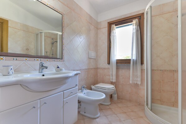 Ein Badezimmer mit Waschbecken, Bidet, Toilette und Duschbereich.