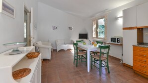 Cocina compacta con una mesa de comedor, sillas, microondas y televisor.
