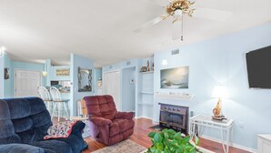 A living room with a dark blue sofa, a brown armchair, a coffee table with a plant, and a fireplace. - Sunset Retreat 2 Bedroom Pet-Friendly Condo at Oyster Point (Kill Devil Hills)