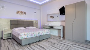 Una camera da letto con un letto, comodino, cassettiera, toletta e TV a parete.