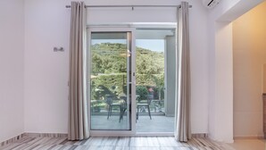 Una stanza con una porta scorrevole in vetro che si apre su un patio esterno con tavolo e sedie.
