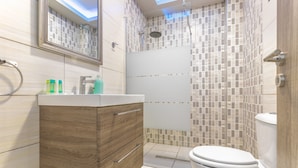 Ein modernes Badezimmer mit einem Holzwaschtisch, einer Glasdusche und einer weißen Toilette.