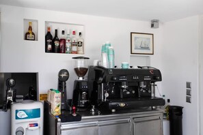 A bar area with a coffee machine, a blender, and a selection of beverages.