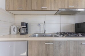 Une cuisine moderne équipée d’une machine à café, d’un évier, d’une cuisinière et de meubles de rangement en bois.
