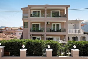 Un edificio residencial de varios pisos con balcones, cielo despejado y montañas al fondo.