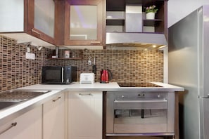 A compact kitchen with a microwave, toaster, coffee maker, and built-in oven.
