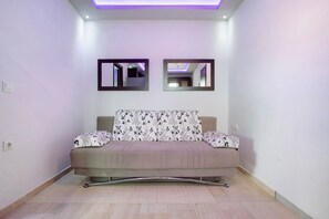 A modern living room with a sofa, two wall-mounted mirrors, and a ceiling light.