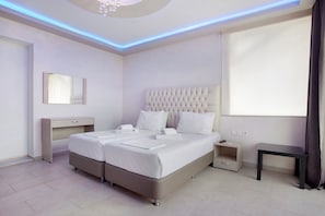 A modern hotel room with a large bed, bedside tables, a desk, and a ceiling light fixture.