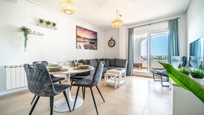 A modern living room with a dining area, a sofa, a coffee table, and a balcony with a view. - Apartment "Casa Verde" with Mountain View, Shared Pool & Wi-Fi (Roldán)