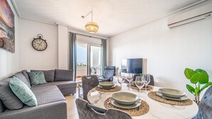 A modern living room with a sofa, dining table, chairs, and a TV. - Apartment "Casa Verde" with Mountain View, Shared Pool & Wi-Fi (Roldán)