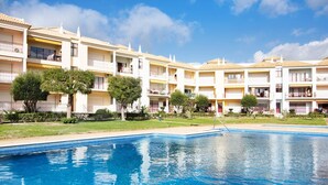A hotel with a swimming pool, multiple balconies, and a clear sky. - Apartment "Columbus Beach" with Sea View, Shared Pool & Wi-Fi (Quarteira)