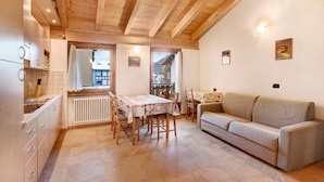Une cuisine avec une table à manger et des chaises, un canapé et un radiateur.