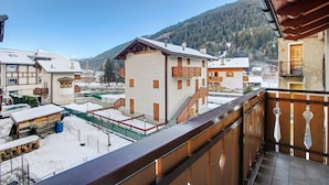 Un bâtiment doté d’un balcon, d’un escalier et offrant une vue sur un paysage enneigé avec des montagnes.