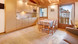 Un intérieur en bois comprenant une cuisine, un coin repas et un balcon.