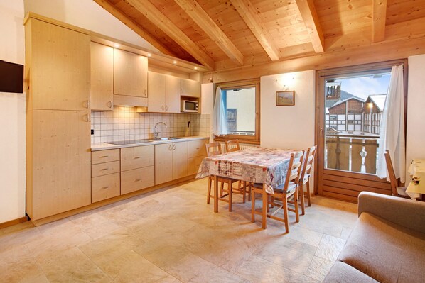 A wooden interior with a kitchen, dining area, and a balcony.