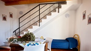 A staircase with a metal railing, a dining table with chairs, a small bed with a blue mattress, and two framed pictures on the walls. - Holiday Home 'Paese Albergo - Arconides' with Sea View, Balcony and Wi-Fi (Motta D'affermo)