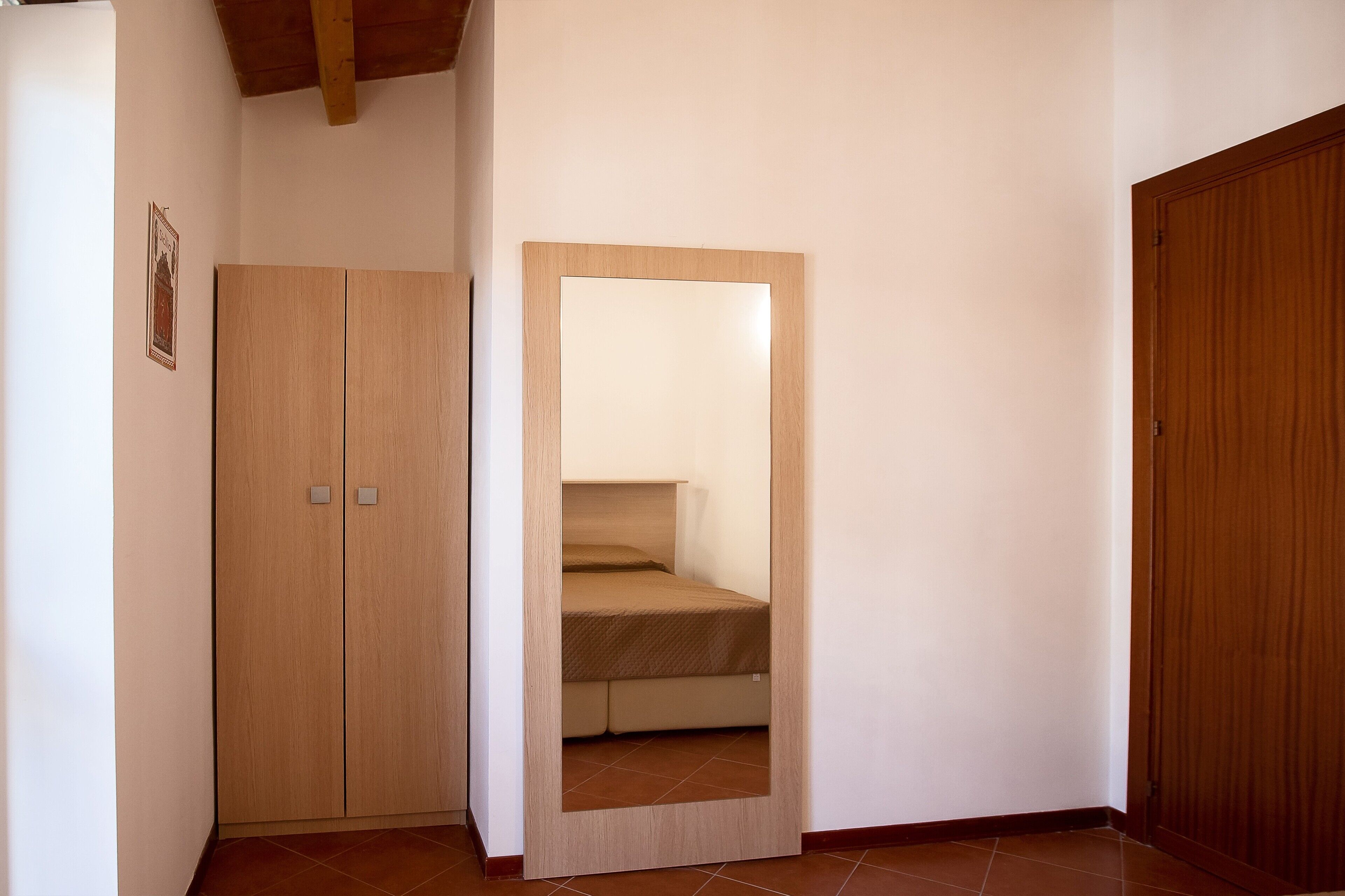 Une chambre à coucher avec une armoire en bois, un miroir et un lit.