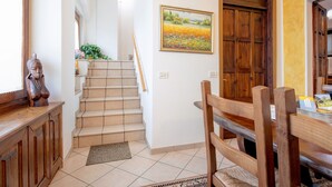 Una escalera conduce a un comedor con una silla de madera y un cuadro en la pared.