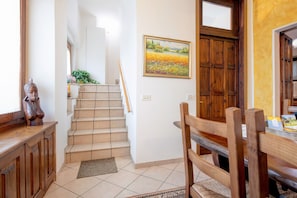 A staircase leading to a dining area with a wooden chair and a painting on the wall.
