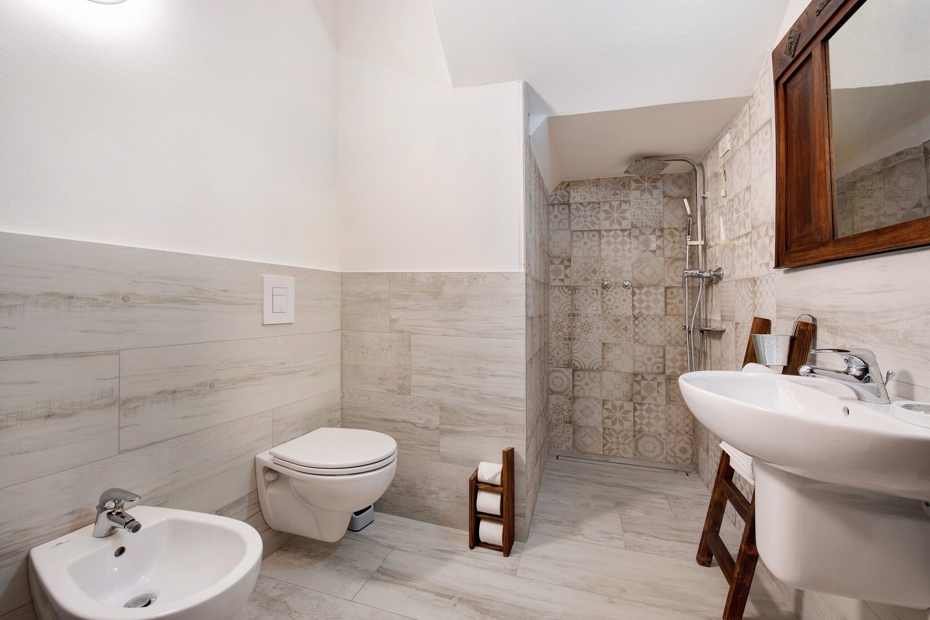 A bathroom with a bidet, toilet, sink, and shower area.