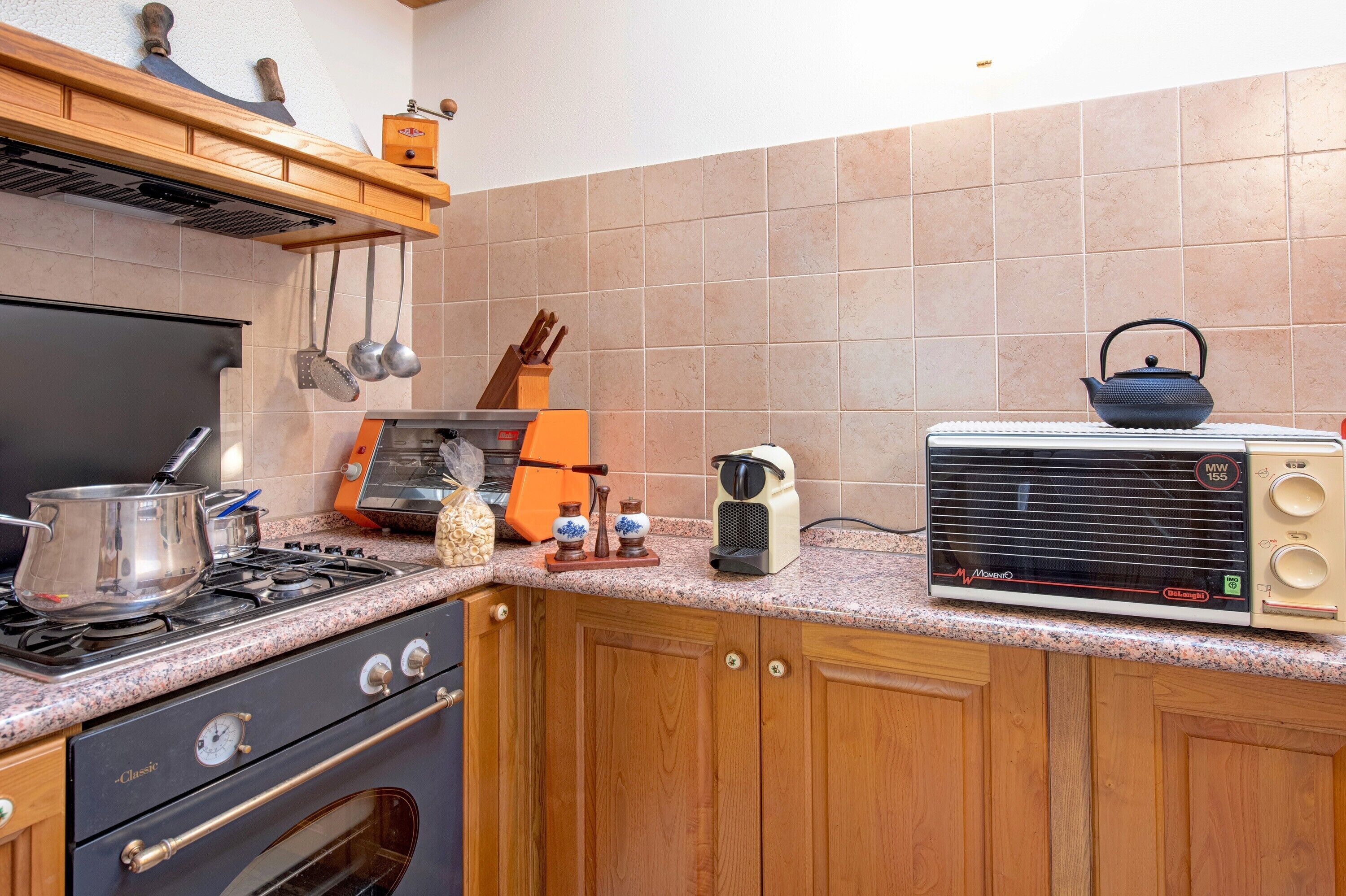 Uma cozinha com fogão a gás, forno, micro-ondas e um rádio antigo.