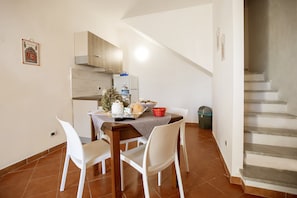 Un coin repas avec une table dressée pour deux personnes, une cuisine en arrière-plan et un escalier menant à un autre niveau.