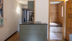Une cuisine compacte dotée d’une cuisinière intégrée, d’un petit coin repas et d’une chambre avec un plancher en bois.