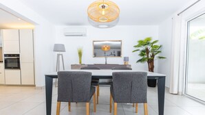 Una cocina moderna con armarios blancos, horno empotrado y zona de comedor con una mesa y cuatro sillas.