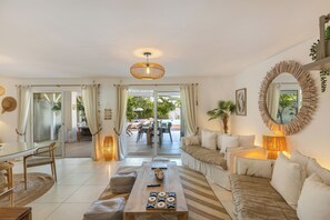 A spacious living area with a glass door leading to a poolside area, a wooden coffee table, and a comfortable seating arrangement.