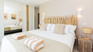 Una habitación de hotel moderna con una cama grande, un espejo y una lámpara de pared.