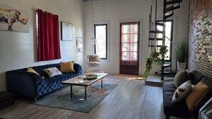 A living room with a blue sofa, a hanging chair, a coffee table, and a staircase.