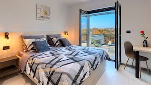 A modern bedroom with a large bed, a desk, and a view of the outdoors. - In a Small Village Surrounded by Nature (Barban)