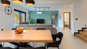 A modern living room with a sofa, a dining table with chairs, and pendant lights. - In a Small Village Surrounded by Nature (Barban)