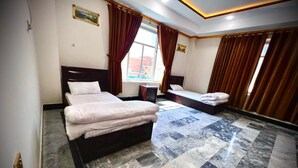 A hotel room with a large bed, a smaller bed, a desk, and a window with curtains. - Apple Hotel and Restaurant (Timergara)