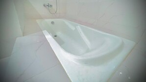 A bathroom with a bathtub, a shower, and tiled walls. - Apple Hotel and Restaurant (Timergara)