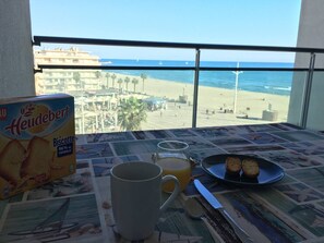 Ein Frühstückstisch mit einer Packung Heudebert Biscotte, einer Tasse, einem Glas Orangensaft, einem Teller mit zwei Keksen und einem Messer.