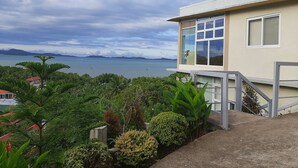 Un edificio moderno con grandes ventanales que dan a una masa de agua y islas distantes.