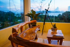 A wooden bench with a view of a body of water and greenery through a window. - Mamima BnB (Caramoan)