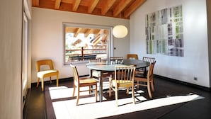 Un espace repas doté d’un plafond en bois, d’une grande fenêtre et d’une œuvre d’art moderne accrochée au mur.