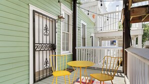 A porch with a green exterior, white railings, and yellow chairs.