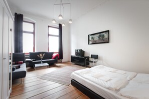 Una habitación moderna con cama, sofá, televisor y un cuadro en la pared.