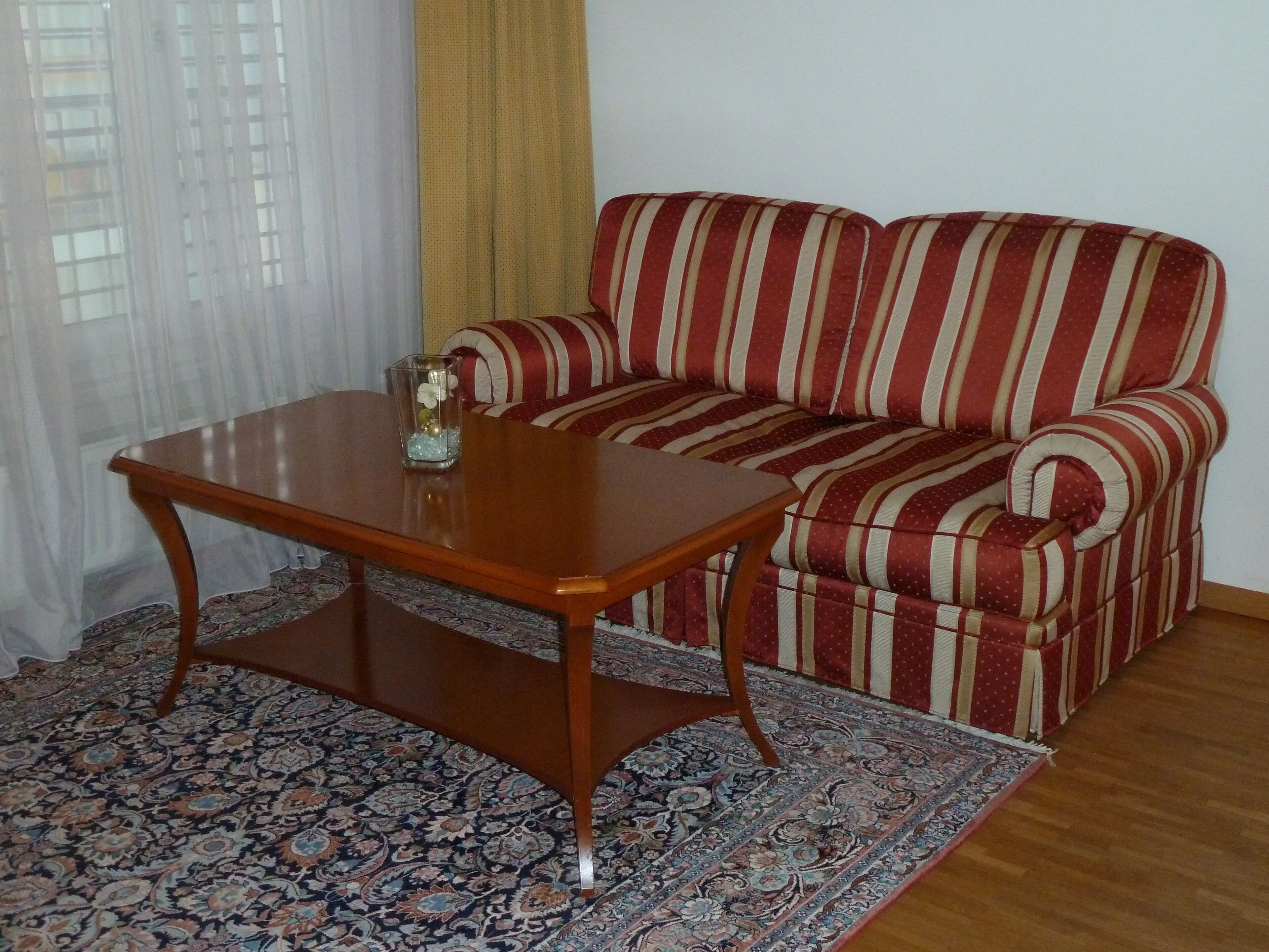 A living room with a sofa, a wooden coffee table, and a patterned rug.