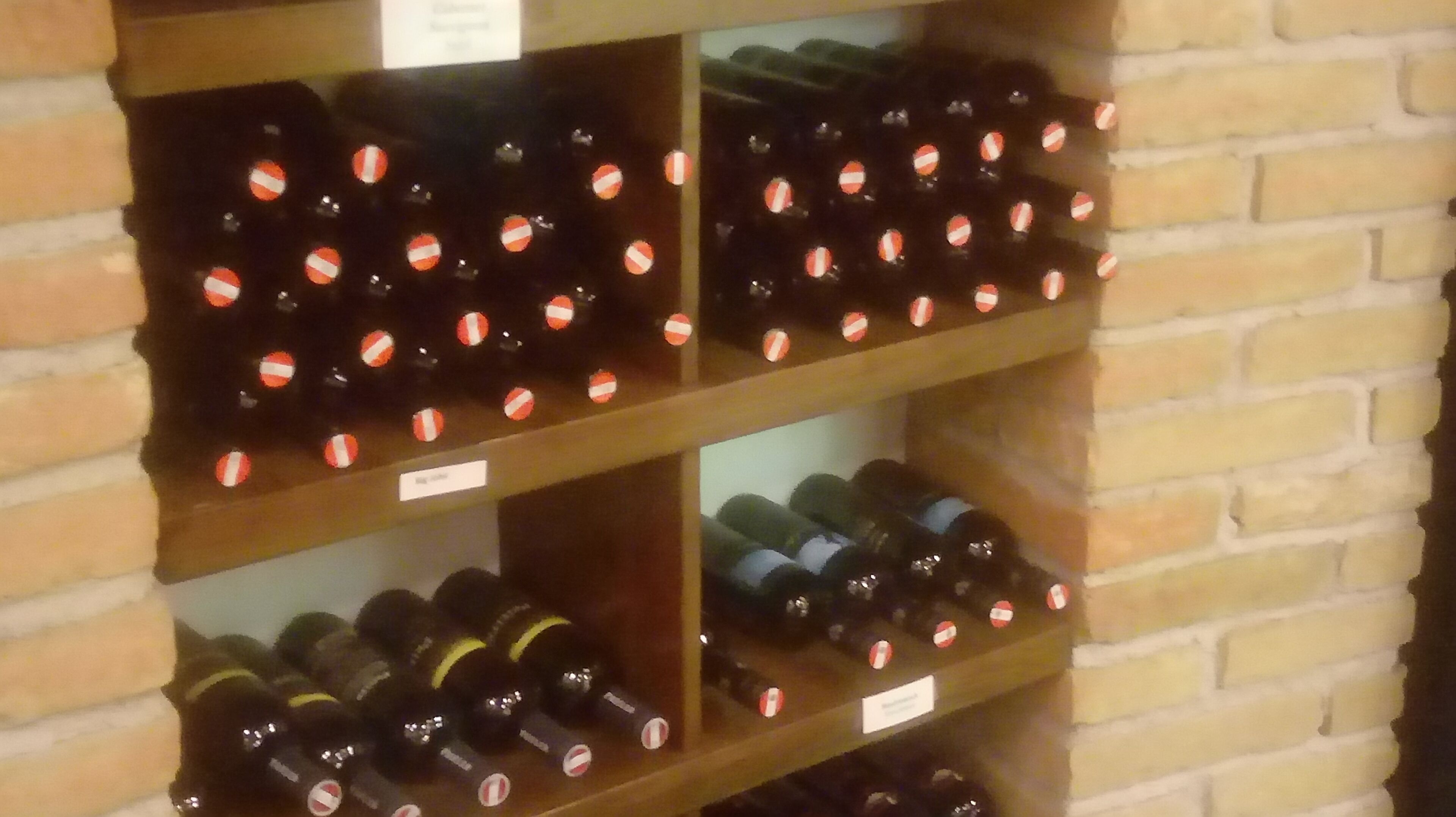 A wine rack with multiple bottles, each labeled with a name tag.