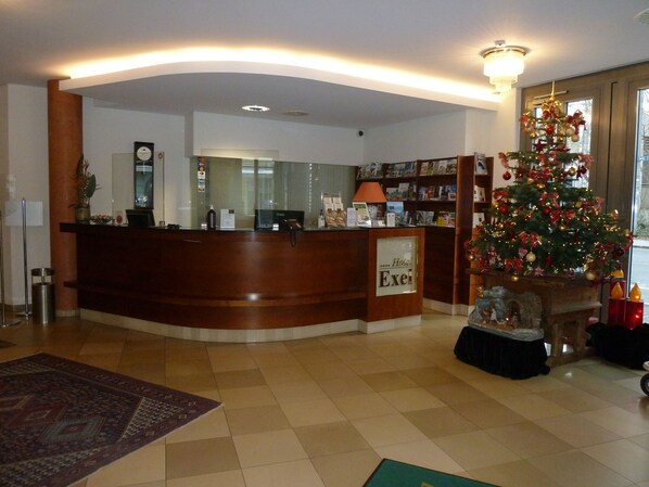 A reception area with a wooden reception desk, a Christmas tree, and a fireplace.