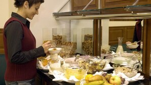 Un bufé con diversos alimentos y una persona sirviéndose.