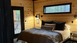 Un dormitorio con cama, ventilador de techo, ventana y puerta.