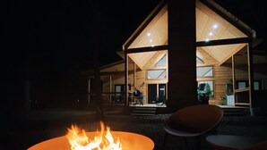 Un espacio moderno al aire libre con una chimenea y una estructura de madera con paredes de vidrio.